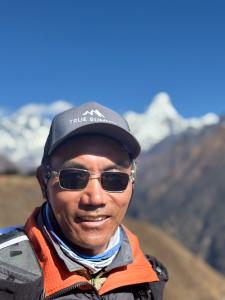 Kami Rita Sherpa stands in front of Ama Dablam and Mount Everest