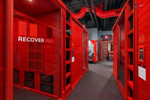 The hallway of a large wellness facility with recover red rooms glowing from red light therapy devices.