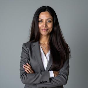 Dr. Kartiki Churi, Chief Medical Officer and psychiatrist at Axis Integrated Mental Health, wearing a gray blazer and white blouse, standing with arms crossed against a neutral background, conveying confidence in the high quality psychiatric services she