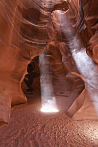 Sunbeams shining through Upper Antelope Canyon with airborne sand highlighting shafts of light.