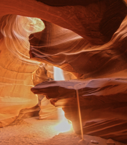 Natural sandstone arch inside Antelope Canyon with warm light reflecting off the canyon walls and sand.
