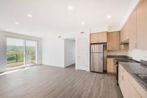 Open-concept living room and kitchen at La Costa Family Apartments with large windows, natural light, and modern finishes