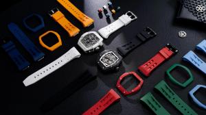 Interchangeable Tsar Bomba watch components including multiple colored straps, bezels, crown covers, and two skeleton‑style watches arranged on a black textured surface.