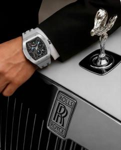 Person wearing a Tsar Bomba watch with a gray strap while resting their hand on a Rolls‑Royce hood ornament and badge.