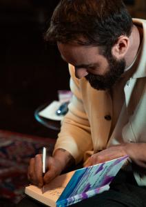 Charlie Cox leans over a copy of The Razor's Edge, inscribing it with "This Book Changed My Life"