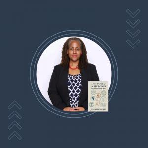 Professional portrait of Jennifer Erie with a blue background wearing a dark blazer, with her book The World in My Bones: The Diplomat Queens Made displayed beside her