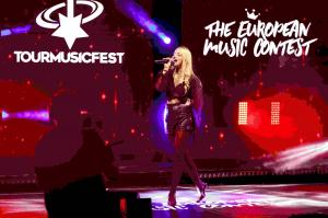 Singer performing live on stage at Tour Music Fest during The European Music Contest, with red stage lighting and audience filming in the foreground.