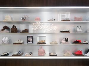 Display wall inside Fila’s flagship store in Taipei, featuring sneakers, bags, and accessories arranged in a sleek, minimalist retail setting with soft lighting and a glowing central sign.