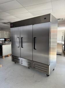 Stainless steel three-door commercial reach-in refrigerator in HorecaStore showroom for restaurant kitchen storage and refrigeration.