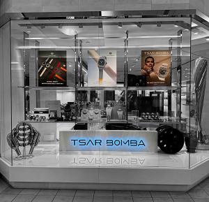 Tsar Bomba retail display with illuminated brand signage, watch showcases, and large posters featuring interchangeable watches, a skeleton model, and a lifestyle wrist shot inside a modern store environment.