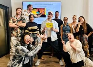 Team celebrating the $27 million Cyberpunk Trading Card Game Kickstarter campaign in front of a screen displaying the project’s success metrics