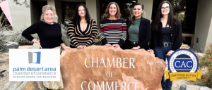 Five women standing behind a stone engraved with "Chamber of Commerce" outside a building, with Palm Desert Area Chamber and CAC logos.