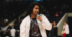 Close-up of Ashwin Gane singing into a microphone during a live NBA halftime performance.