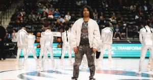 Ashwin Gane performing on an NBA court with backup dancers during a halftime show in a packed arena.