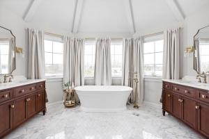 a master bath remodel in carmel indiana by worthington design & remodel featuring a free standing white porcealin tub, marble floors and cherry finished cabinetry with brass hardware