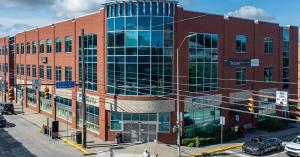 Exterior view of 1700 Murray Avenue, a three-story Class A office building with a curved glass facade at the corner of Murray and Forbes Avenues in Pittsburgh's Squirrel Hill neighborhood.