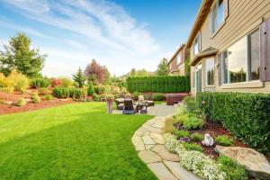 A manicured green lawn featuring a flagstone path, outdoor patio furniture, and vibrant flower beds in a Sonoma County backyard.