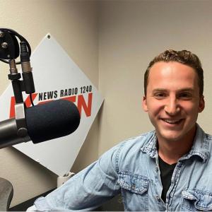 A smiling Aaron Cherry sitting behind a professional studio microphone in front of the KQEN News Radio 1240 logo.
