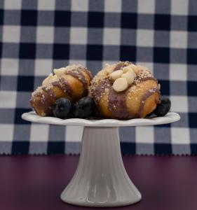 Photo of mini donuts on a pedestal with a blueberry glaze topping and white chocolate chips