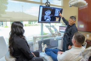 Top Roseville dentist Dr. Arthur Kwan explaining dental implants procedure to patient at Nu Smile Roseville Dental
