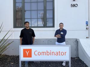 Pulkit Gupta and Agnay Srivastava stand in front of the Y Combinator sign.