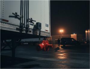A nighttime photograph of the back of a shipping container, featuring close-up view of seals securing the container.