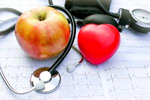 photo of a patient chart with a stethescope, an apple and a big red heart signifying Holistic wellness and nursing