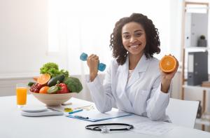 photo of a holistic nurse in a white uniform sitting with a table of fruits and vegetables