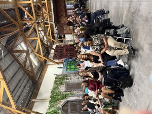 A diverse crowd of aspiring models and actors seated in rows inside a spacious Hollywood production studio with exposed wooden beam ceilings and film set backdrops, attending a VIP Ignite live industry event as part of the organization's 20-year history o