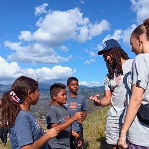International Samaritan scholarship students are talking with Avonte Maddox, a defensive back for the Detroit Lions, on a hill overlooking their community in Tegucigalpa, Honduras, near the dumpsite.