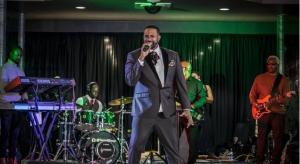 Tony Tatum singing on stage with his band during a live performance.
