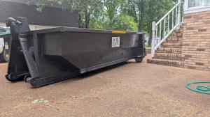 Trash Pandy black 10 yard roll-off dumpster on residential driveway for home cleanout project