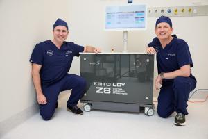 Dr David Gunn and Dr Brendan Cronin crouching next to two Ziemer Z8 femtosecond laser