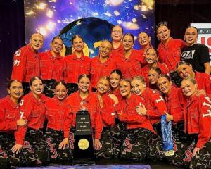 Dance Athletics Denver team celebrates on stage with trophy after winning The Dance Worlds, showcasing their achievement as a three-time dance world’s champion.