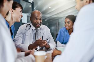 photo of a health care team sitting at a conference table with the manager leading a meeting
