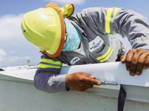 McAllen Valley Roofing Co. worker installing a commercial roof during COVID-19 while wearing a mask.