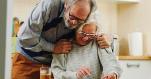 Senior couple at a kitchen table reviewing life insurance policy documents together.