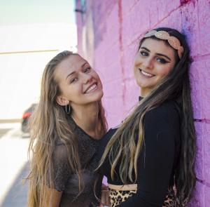 Two young women smiling together in a close friendship moment.