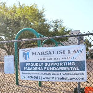 Marsalisi Law sponsorship banner displayed on a chain-link fence at Pasadena Fundamental Elementary School in St. Petersburg, FL