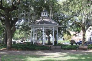 Whitefield Square in Savannah, Georgia, featuring a white gazebo surrounded by large oak trees draped with Spanish moss. A recent archaeological ground-penetrating radar survey identified potential unmarked African burial sites beneath the historic public