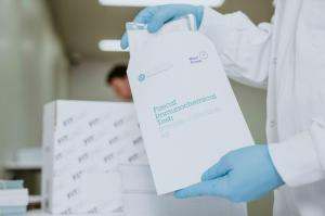 Photo shows a Mast Group FIT patient test kit being taken out of its outer packaging.
