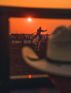 A cowboy rides a bucking horse at sunset at a rodeo arena in Lincoln, Nebraska.