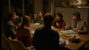 Group of friends and family enjoying a warm, intimate multi-course meal together around a beautifully set wooden dining table in a private home during a Supper at Home dinner experience.