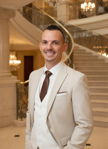 Joe Carter in a cream suit standing in front of an elegant staircase inside a luxury venue.