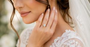Bride wearing oval moissanite engagement ring by Dloria Fine Jewelry on ring finger, featuring high clarity center stone in gold setting, showcasing modern fine jewelry design, timeless elegance, and refined bridal style in soft natural lighting