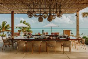 The stylish outdoor bar and open-air dining area at Ámbra Beach Club & Restaurant on Long Bay Beach, Providenciales, a premier Turks and Caicos beach club and restaurant featuring woven light fixtures and panoramic views of the turquoise Caribbean water.