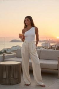 Model in off the shoulder top and pants at sunset with a cocktail