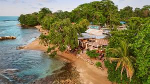 Aerial view of GigiO Restaurant Puerto Viejo Costa Rica at dusk, showing the checkered outdoor terrace with dining tables, thatched palapa huts, and the illuminated Caribbean-style dining room and lounge.