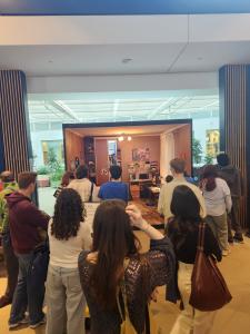 A crowd of people viewed from behind looking into an exhibition space designed to identically replicate the bedroom of a deported Ukrainian teenager.