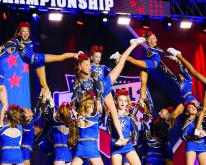 Young athletes perform advanced stunts during a competition routine, representing the launch of Cheer Athletics Carlisle and new opportunities for cheerleaders in Northern England.